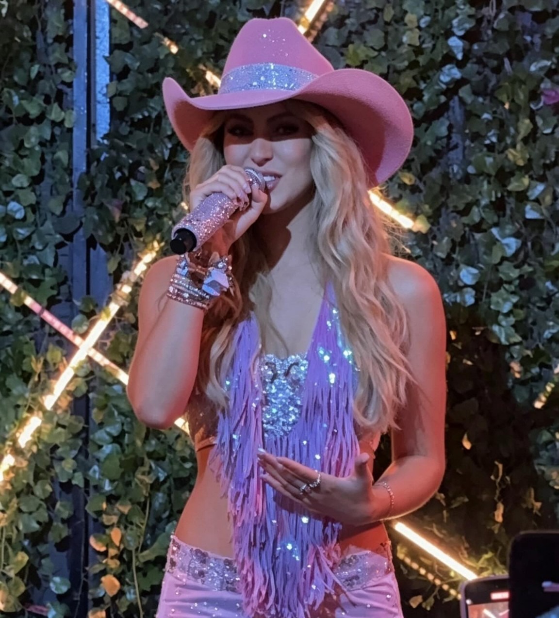 Jessy Portilla se apresentando no palco com chapéu rosa e microfone